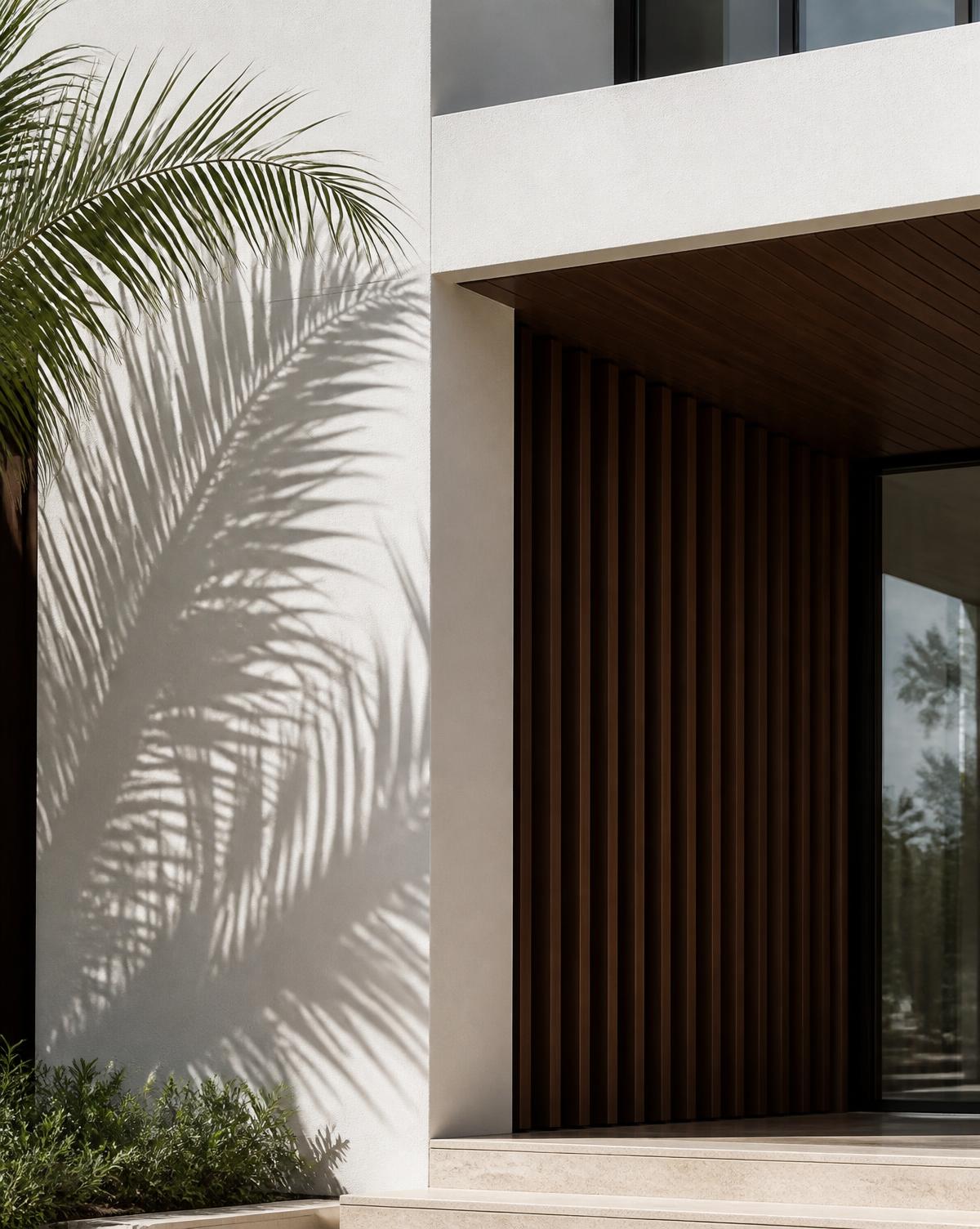 Architectural detail of a modern residence with palm shadows on a white facade